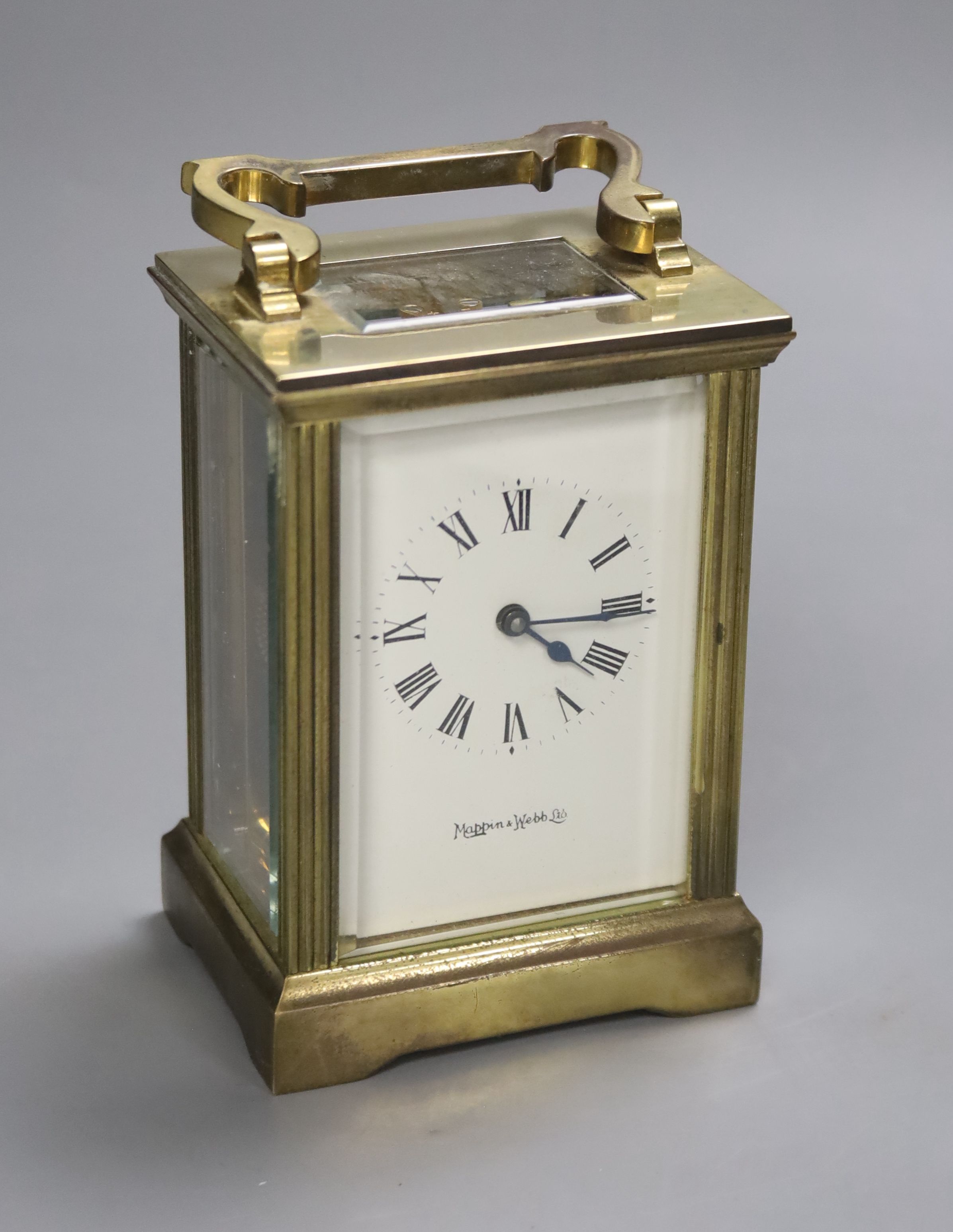 An early 20th century brass carriage timepiece, retailed by Mappin & Webb Ltd, black Roman numerals on a white dial, 8cm wide 15cm high (max.)